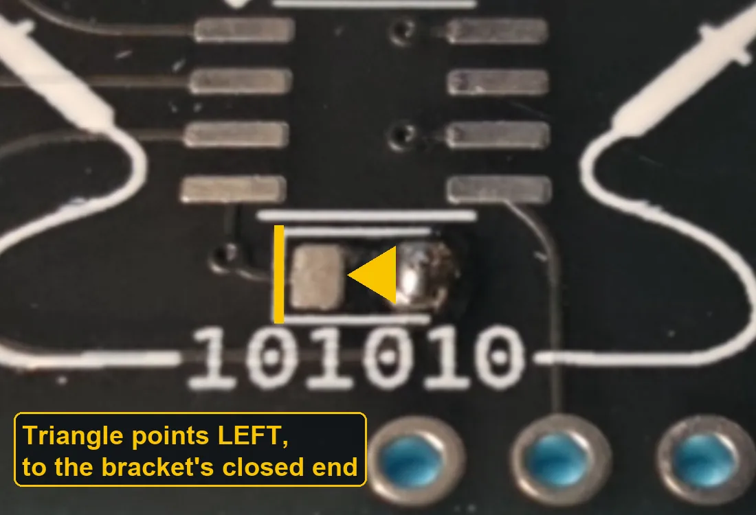 The LED pads on the board inside a white bracket; the bracket's closed left side is highlighted and a yellow triangle between the pads points left toward it